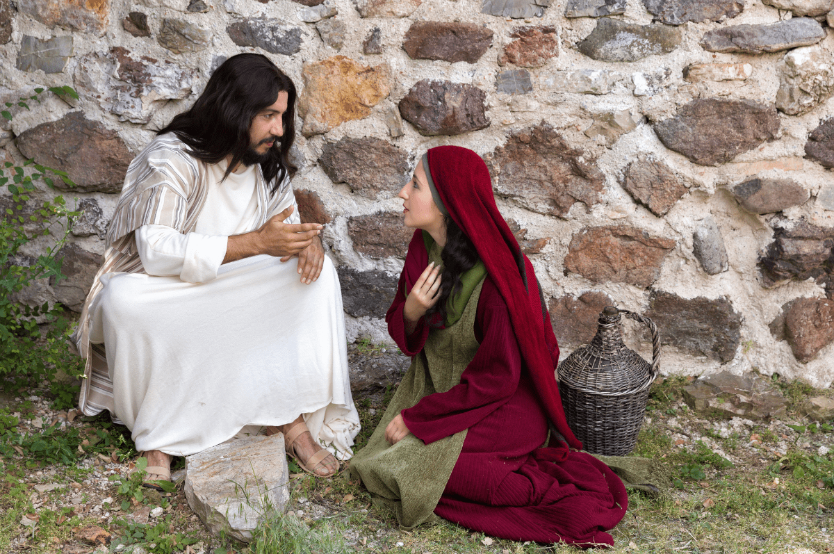 Jesus speaking to a woman seated on the ground.