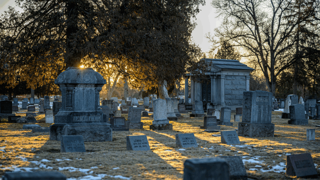 Gravestones and mausoleum in a cemetery lit by late afternoon sun.